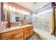 Main bathroom featuring double sinks, decorative mirrors, and a glass door shower at 14912 W Lamoille Dr, Surprise, AZ 85374