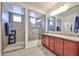 Bathroom featuring double sink vanity, large mirror and tiled walk-in shower with glass enclosure at 16140 W Sierra St, Surprise, AZ 85379