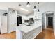 Bright kitchen boasts a granite-topped island with a sink, white cabinets, stainless appliances and hardwood floors at 11822 W Softwind Dr, Sun City, AZ 85373