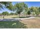 Community park providing a large grassy area with mature trees and a paved walkway for leisurely activities and relaxation at 11822 W Softwind Dr, Sun City, AZ 85373