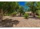 The backyard is landscaped with mature trees and gravel for easy maintenance at 15460 W Amelia Dr, Goodyear, AZ 85395