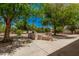 An inviting backyard showcasing mature trees, hardscape, and a tiered stone retaining wall at 15460 W Amelia Dr, Goodyear, AZ 85395