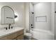 Bathroom featuring a unique mirror, white tiled shower and tub, and a marble countertop sink at 3323 N 81St St, Mesa, AZ 85207