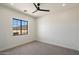 Bright bedroom featuring neutral carpet, modern ceiling fan, and mountain views from the window at 3323 N 81St St, Mesa, AZ 85207