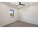 Bright bedroom featuring neutral carpet, modern ceiling fan, and view of desert landscape from window at 3323 N 81St St, Mesa, AZ 85207