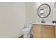Clean bathroom with a round mirror, light wood cabinets, and modern fixtures, showcasing a tidy space at 4712 E Amberwood Dr, Phoenix, AZ 85048