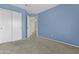 Bedroom with neutral carpet and blue painted walls, featuring a closet and bathroom access at 4712 E Amberwood Dr, Phoenix, AZ 85048