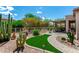 Landscaped backyard with artificial turf, desert plants, and a covered patio at 5381 S Emerald Desert Dr, Gold Canyon, AZ 85118