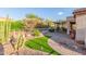 Beautifully landscaped backyard featuring artificial turf, desert plants, and a covered patio at 5381 S Emerald Desert Dr, Gold Canyon, AZ 85118