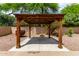 Well-manicured backyard with a cozy wooden gazebo on a concrete patio surrounded by colorful plantings at 9154 E Caribbean Ln, Scottsdale, AZ 85260