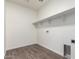 A laundry room with wooden-look tile floor, white walls, floating shelves, and hookups for a washer and dryer at 9486 W Sandstone Mountain Dr, Casa Grande, AZ 85194