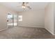 Bright bedroom with a ceiling fan, a sliding glass door, and neutral carpet at 12238 W Monroe St, Avondale, AZ 85323