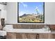 A luxurious soaking tub offers scenic views of the mountains through a large window at 13209 N 17Th Pl, Phoenix, AZ 85022
