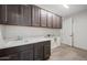 Well-equipped laundry room with ample storage cabinets and a utility sink, adjacent to doorway at 13503 W Calle De Baca --, Peoria, AZ 85383