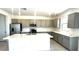 A modern kitchen boasts gray cabinets, stainless steel appliances, and a large island with sink and white countertop at 25151 W Wayland Dr, Buckeye, AZ 85326
