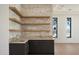 Stylish bar area featuring a stone accent wall, floating shelves, and granite countertops at 6202 E Larkspur Dr, Scottsdale, AZ 85254