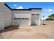 A modern home's exterior showcasing a spacious driveway leading to two garages with white doors and dark trim at 6202 E Larkspur Dr, Scottsdale, AZ 85254