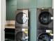 A laundry room with a dual washer and dryer set and custom green cabinetry at 6202 E Larkspur Dr, Scottsdale, AZ 85254