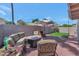 Backyard patio area with green lawn, desert landscaping, and shaded sitting arrangement surrounding a fire pit at 7917 E Cactus Wren Rd, Scottsdale, AZ 85250