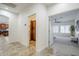 Hallway view showing the laundry room with stacked washer/dryer and cabinetry; bedroom with ceiling fan at 1001 N Quail Ln, Gilbert, AZ 85233