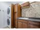 This laundry room includes a stacked washer/dryer, utility sink, cabinets and eye-catching mosaic tile backsplash at 1001 N Quail Ln, Gilbert, AZ 85233