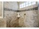 Walk-in shower boasts custom tile work, pebble accents, built-in niche and glass enclosure at 1001 N Quail Ln, Gilbert, AZ 85233