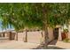 Close-up of a two-car garage featuring desert landscaping, a small tree, and a security sign in the yard at 10652 W Coronado Rd, Avondale, AZ 85392