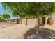 View of a two-car garage with desert landscaping, a tile roof, and a small tree casting a shadow in the driveway at 10652 W Coronado Rd, Avondale, AZ 85392
