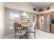 Eat-in kitchen features stainless steel refrigerator, light wood cabinets, and a dining table next to sunlit windows at 10652 W Coronado Rd, Avondale, AZ 85392