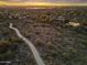 Panoramic aerial view of a community featuring walking path and houses surrounded by desert landscape and city lights at dusk at 10811 E Acoma Dr, Scottsdale, AZ 85255