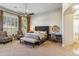 Bright bedroom with a large bed, seating area, shutters, and gold fan at 10811 E Acoma Dr, Scottsdale, AZ 85255