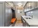 Well-organized laundry room with gray cabinetry, a built-in bench, quartz countertops, and stainless steel appliances at 10811 E Acoma Dr, Scottsdale, AZ 85255