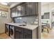 Modern laundry room with gray cabinets, white countertops, subway tile backsplash, and stainless steel appliances at 10811 E Acoma Dr, Scottsdale, AZ 85255