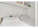 Bright laundry room with a white, front-loading washer and dryer, with shelving above for storage at 1120 N Val Vista Dr # 10, Gilbert, AZ 85234