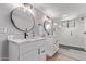 Bright bathroom with dual vanities, round mirrors, and a glass-enclosed shower with black hardware at 113 S Ocean Dr, Gilbert, AZ 85233