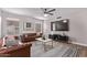 Modern living room featuring leather sofas, a geometric rug, and a large TV, illuminated by a ceiling fan light at 113 S Ocean Dr, Gilbert, AZ 85233