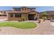 A manicured backyard featuring a plush green lawn, desert landscaping, and a covered patio with stylish outdoor seating at 11466 N 162Nd Ln, Surprise, AZ 85379
