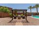 Outdoor seating area with pergola, stylish chairs, a stone fire pit, and desert landscaping, perfect for relaxing and entertaining at 11466 N 162Nd Ln, Surprise, AZ 85379