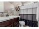 Well-lit bathroom with a modern sink, dark wood vanity, and striped shower curtain at 11466 N 162Nd Ln, Surprise, AZ 85379