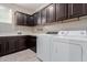 A practical laundry room with dark wood cabinets, white countertops, and modern washer and dryer appliances at 11466 N 162Nd Ln, Surprise, AZ 85379