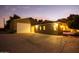 Well-lit exterior of the home with a large garage and cozy outdoor swing for relaxing evenings at 14749 E Pecos Rd, Gilbert, AZ 85295