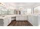 Bright bathroom with dual sinks, white cabinets, wood-look flooring and modern fixtures at 1538 W Wagner Dr, Gilbert, AZ 85233