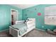 This charming bedroom has bright teal walls and a plush carpet and includes a white wooden bed frame at 18484 W Westfall Way, Surprise, AZ 85374