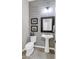 Charming half bath with stylish wood-look accent wall, framed mirror and pedestal sink at 19943 E Strawberry Dr, Queen Creek, AZ 85142