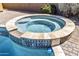 Close-up of a built-in hot tub featuring a spillover into the swimming pool and brickwork tile trim at 19943 E Strawberry Dr, Queen Creek, AZ 85142
