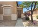 Inviting home entrance with a wooden door, desert landscaping, and mature trees at 204 S Valle Verde --, Mesa, AZ 85208
