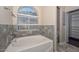 Bathroom featuring soaking tub with stone surround and window at 21532 N 65Th Ave, Glendale, AZ 85308