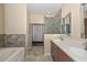 Bright bathroom showcasing a dual sink vanity, soaking tub, and a stone shower with glass door at 21532 N 65Th Ave, Glendale, AZ 85308