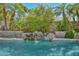 A private pool featuring a tranquil rock waterfall and lush tropical landscaping offers a serene backyard retreat at 21532 N 65Th Ave, Glendale, AZ 85308