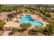 Aerial view of a beautiful community swimming pool surrounded by palm trees, lounge chairs and a building at 22670 E Russet Rd, Queen Creek, AZ 85142